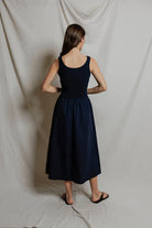 Woman wearing a navy blue dress against a plain white background