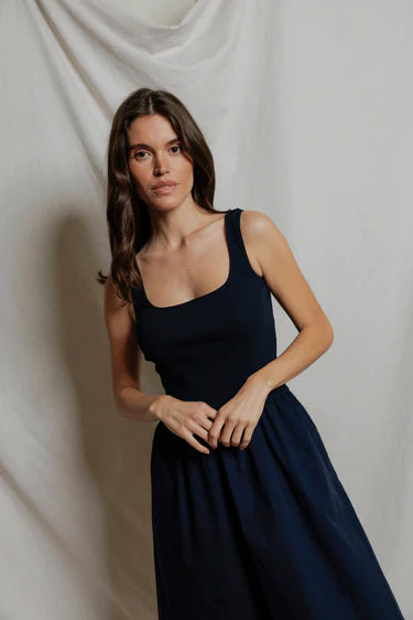 Woman wearing a navy blue dress against a plain background