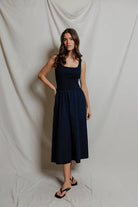Woman wearing a navy blue dress against a plain background