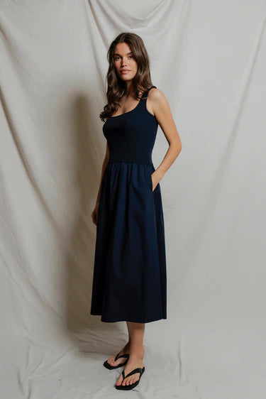 Woman wearing a navy blue dress against a plain white background