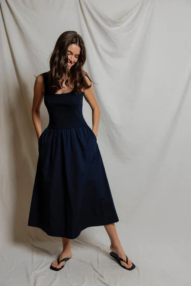 Woman wearing a navy blue dress against a plain background