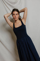Woman wearing a navy blue dress against a plain background