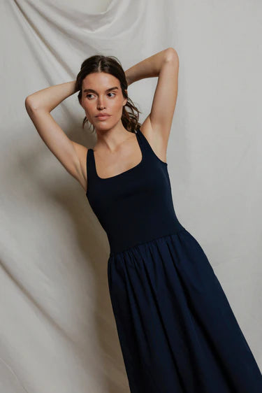 Woman wearing a navy blue dress against a plain background