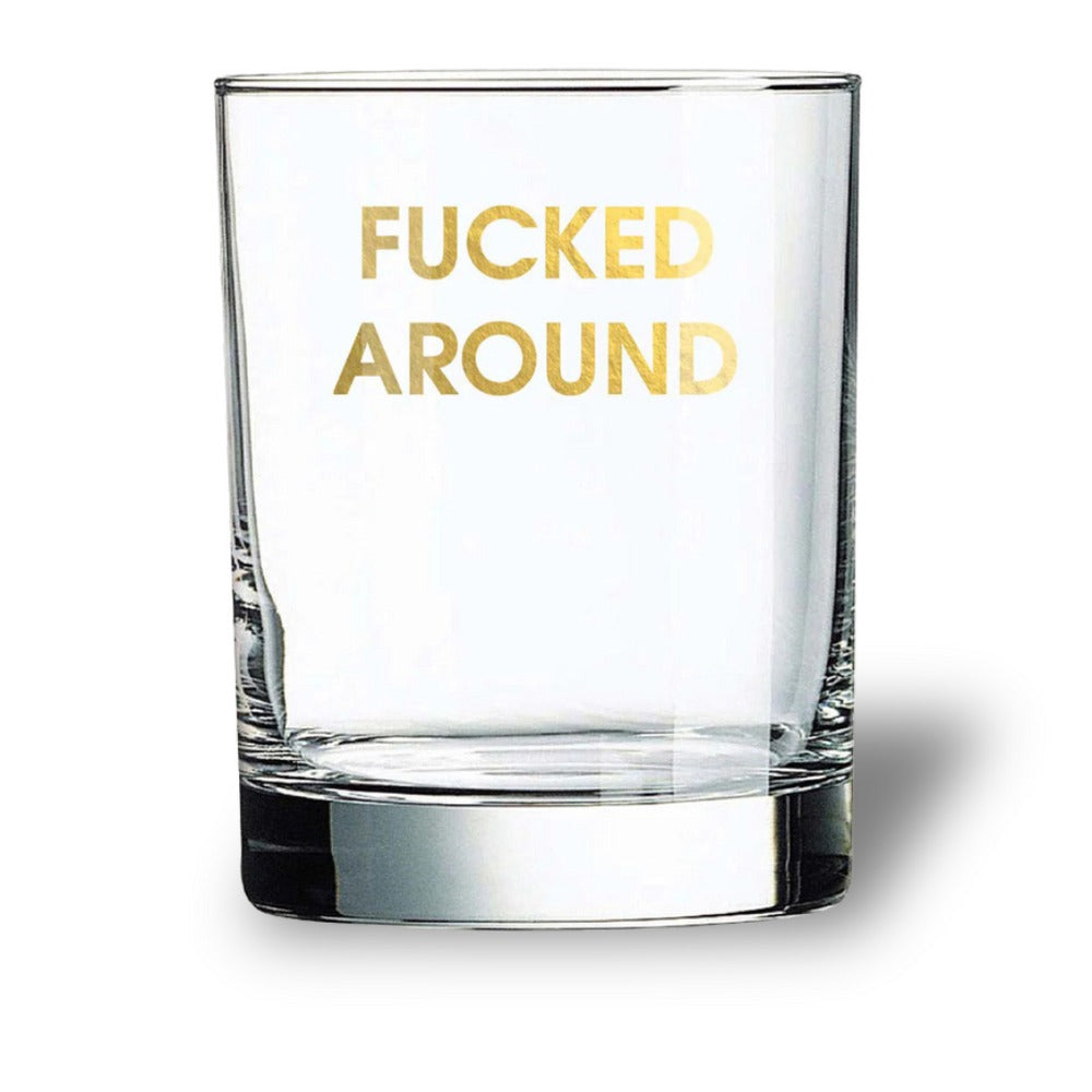Clear glass with gold text 'FUCKED AROUND' on a white background