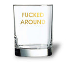 Clear glass with gold text 'FUCKED AROUND' on a white background