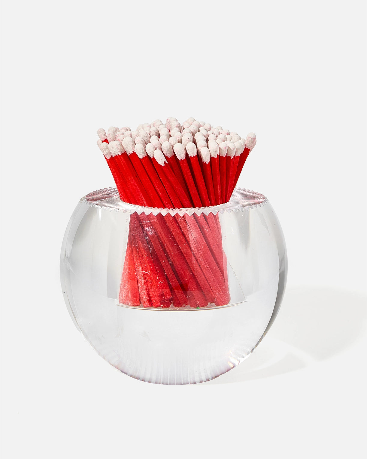 Red matches in a clear glass holder on a white background