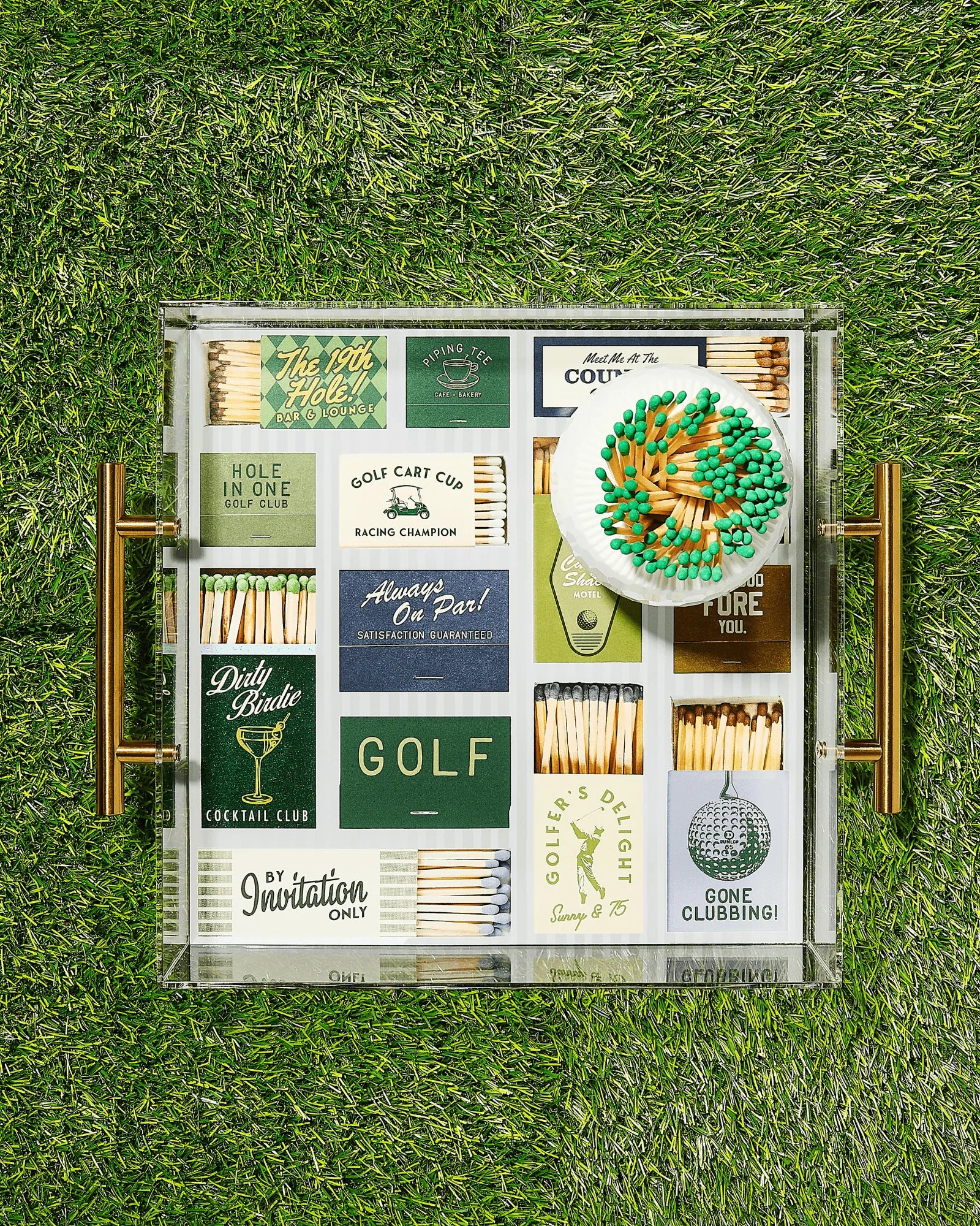 Collection of vintage golf-themed matchbooks in a glass case on grass