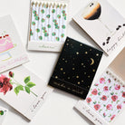 Collection of small notebooks and cards with various designs on a white surface
