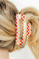 Checkered hair clip in blonde hair against a white background