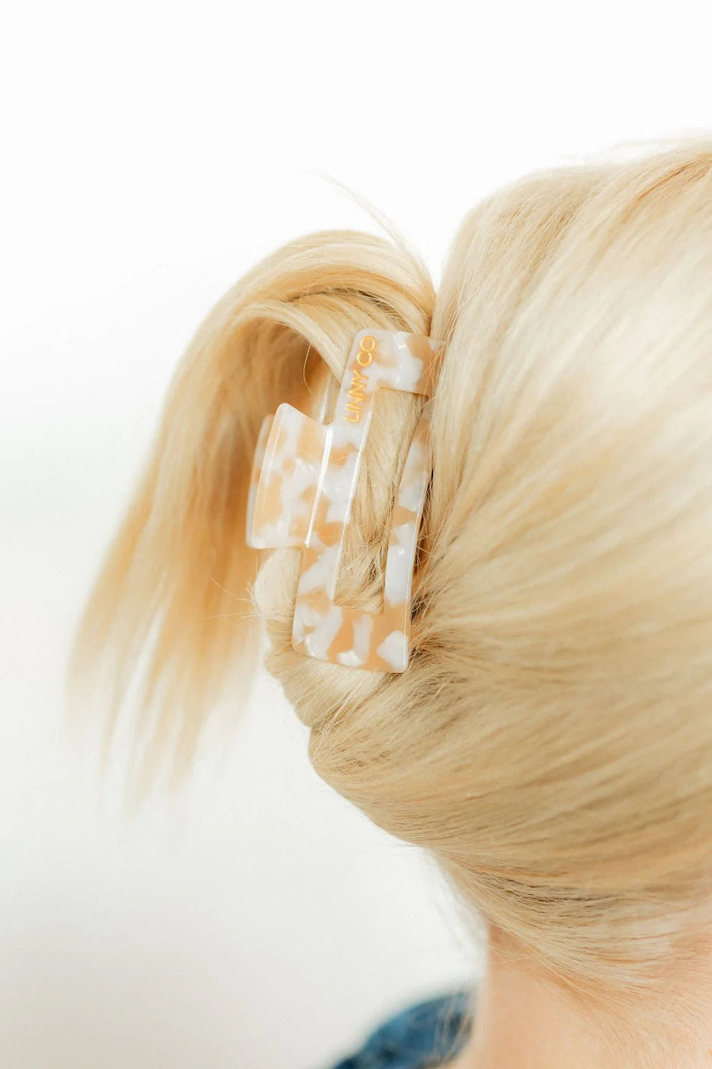Close-up of blonde hair with a decorative hair clip on a white background