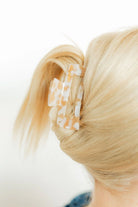 Close-up of blonde hair with a decorative hair clip on a white background
