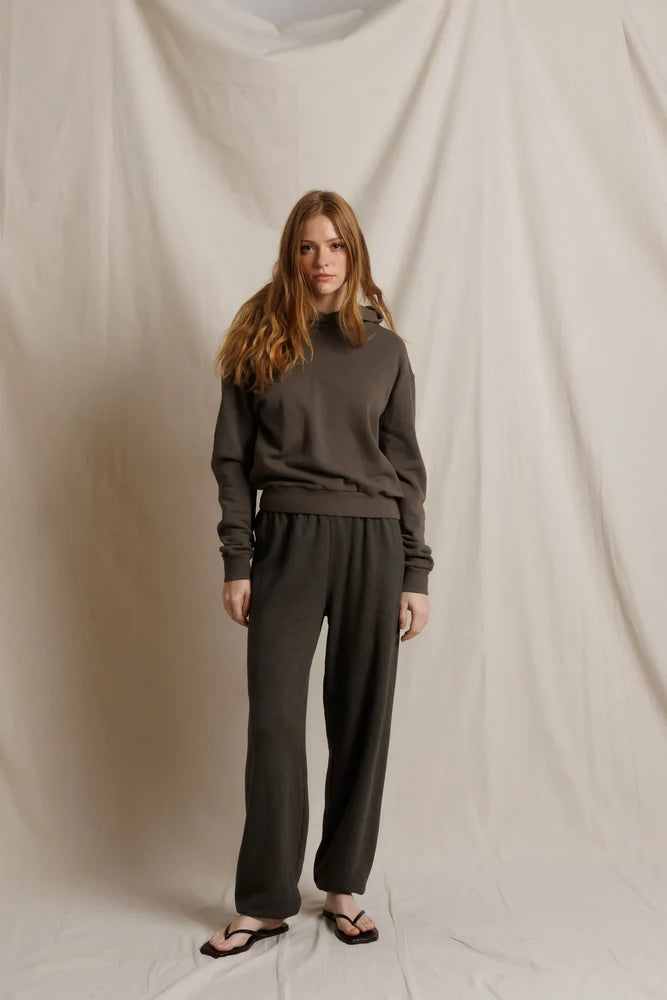 Woman wearing a dark brown outfit against a plain background