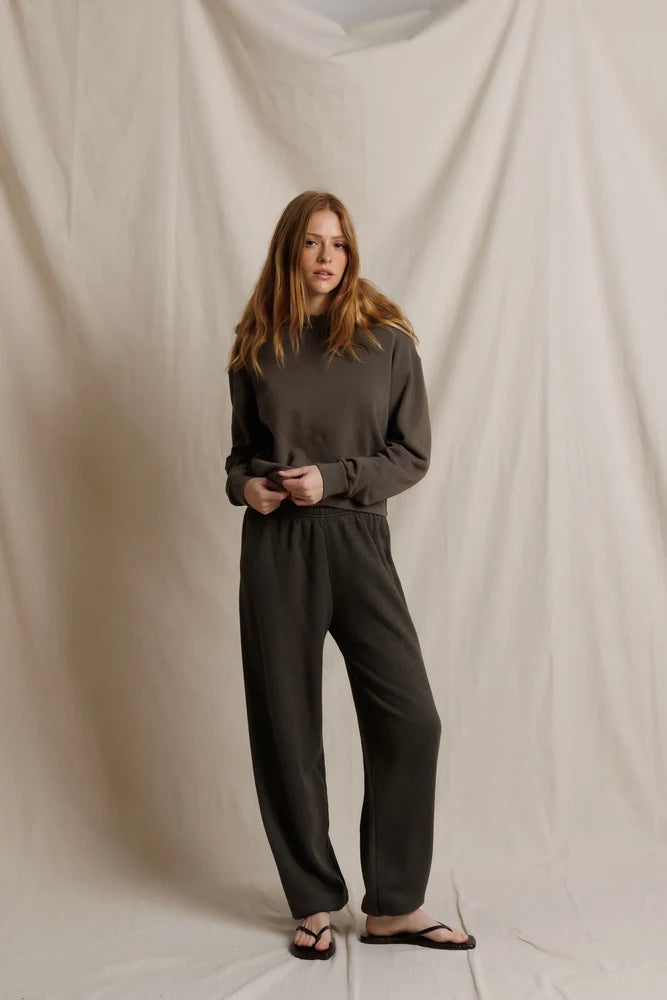 Person wearing a dark gray outfit against a plain background