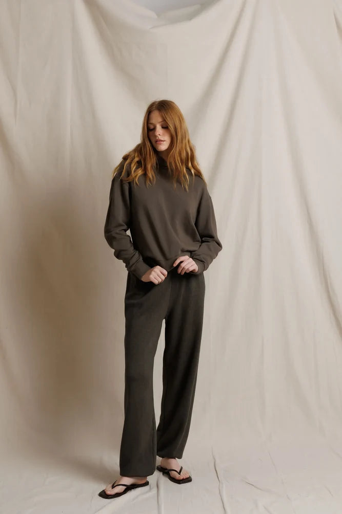 Person wearing a dark gray outfit against a plain background