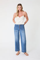 Woman wearing a white top and blue jeans on a white background