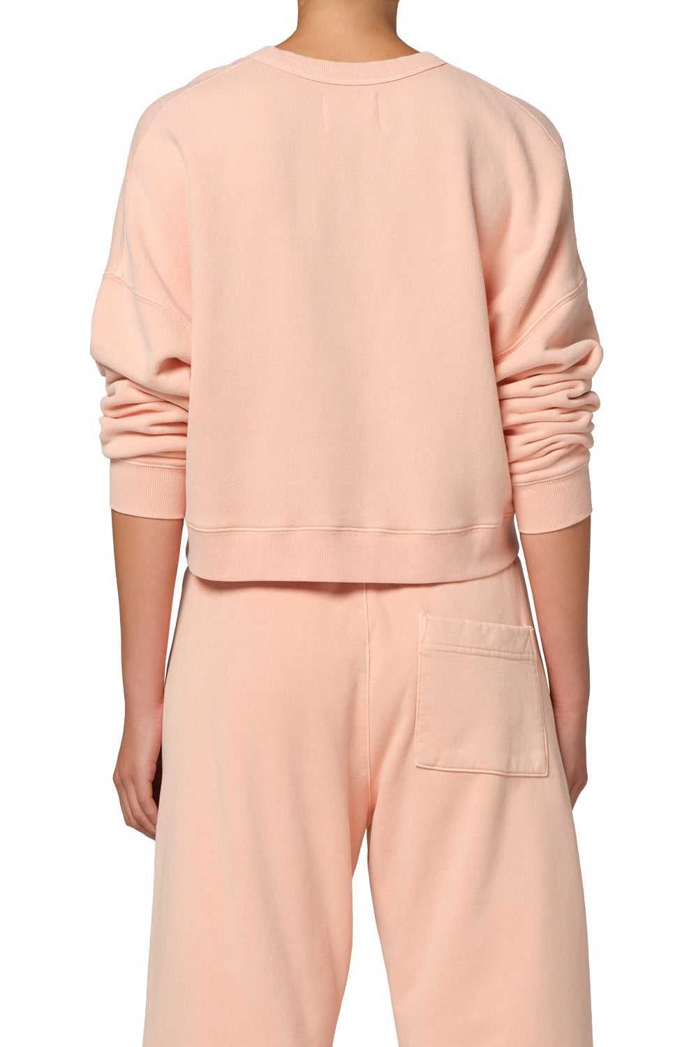 Person wearing a light pink sweatshirt and pants on a white background