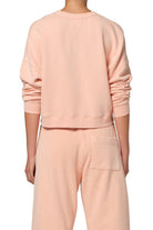 Person wearing a light pink sweatshirt and pants on a white background