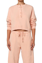 Person wearing a matching pink sweatshirt and pants set on a white background