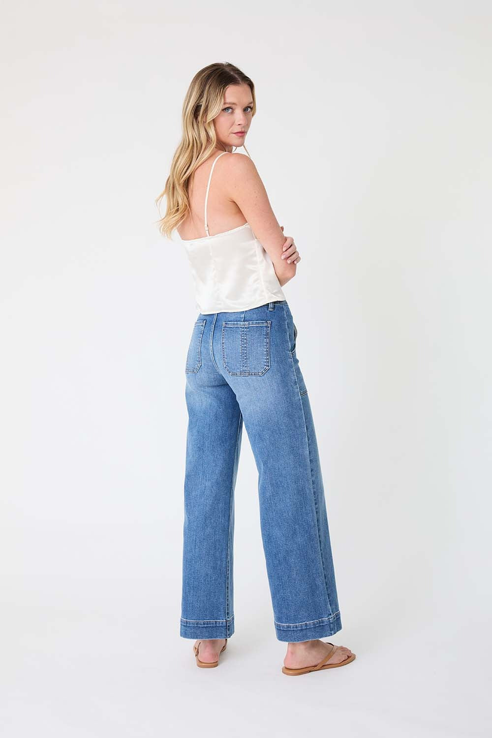 Woman wearing a white top and blue jeans on a white background