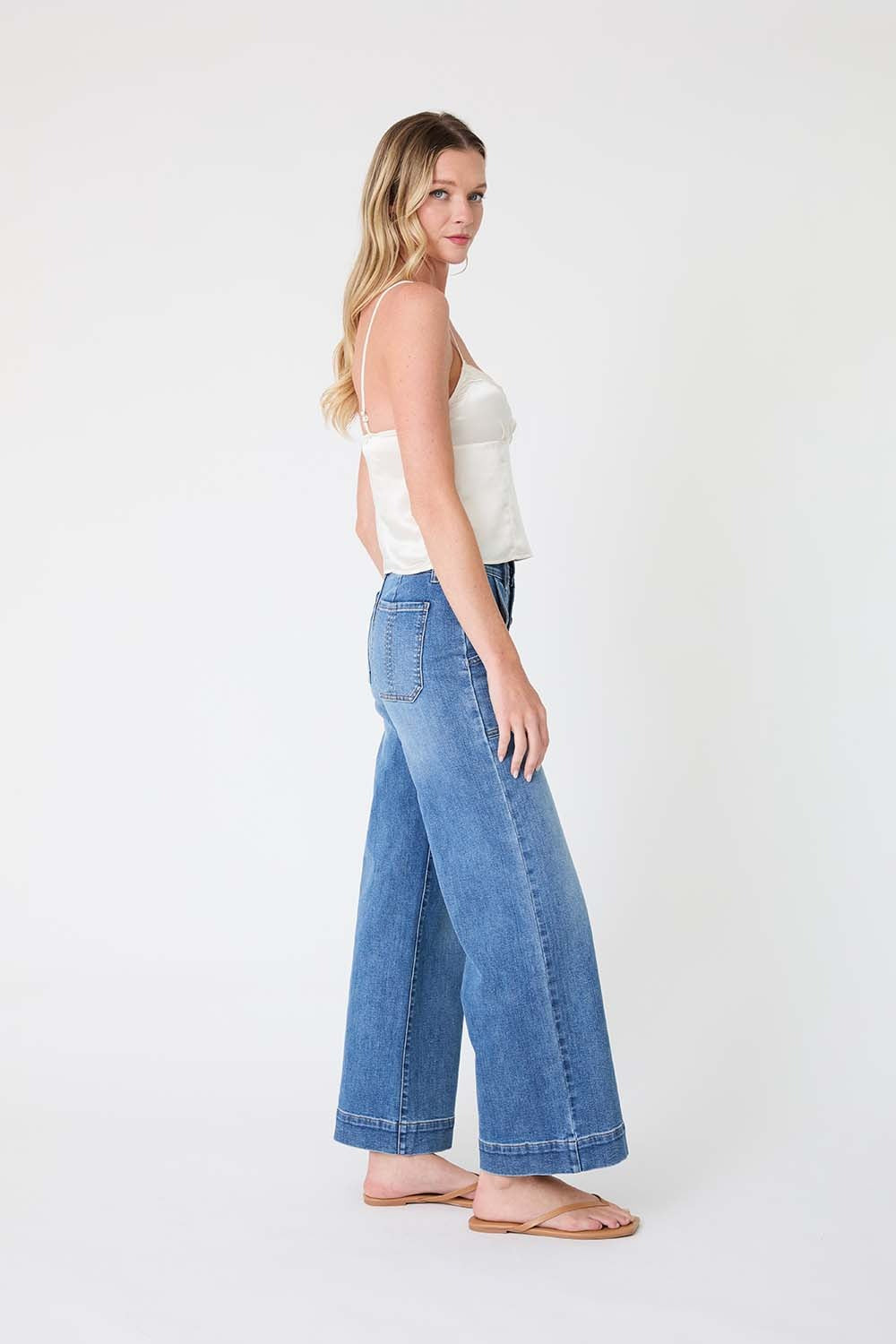 Woman wearing a white top and blue jeans on a white background