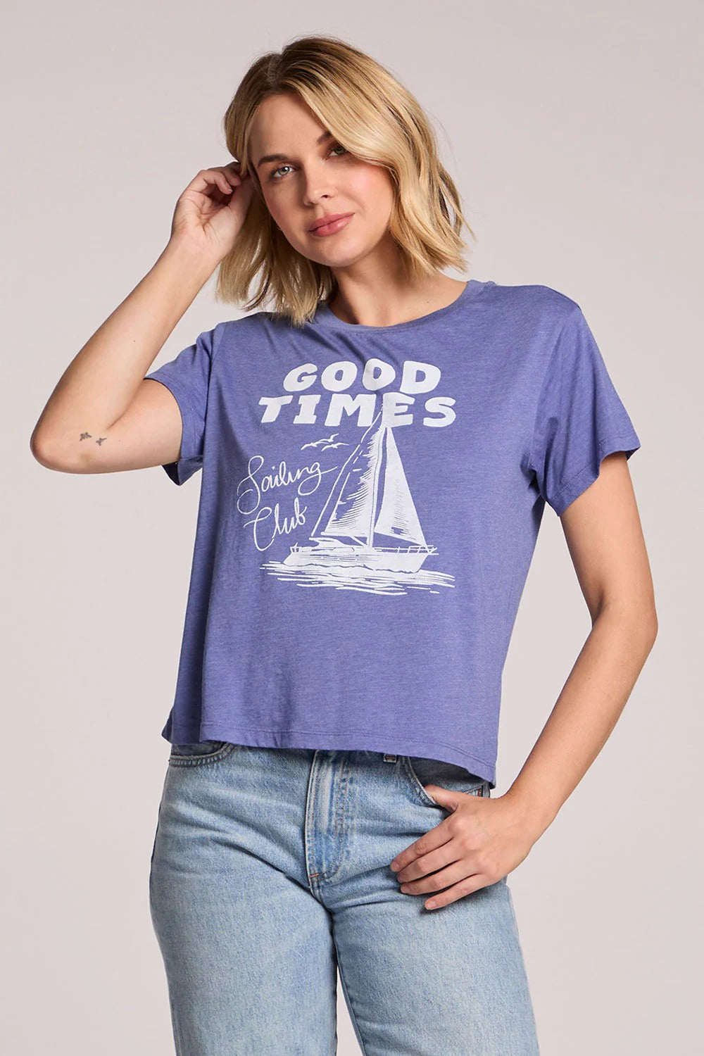 Woman wearing a blue t-shirt with 'Good Times Sailing Club' design on a plain background