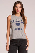 Woman wearing a gray tank top with 'Locals Only' text and heart graphic on a plain background