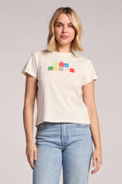 Woman wearing a cream t-shirt with colorful text design on a plain background