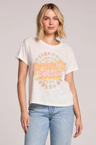 Woman wearing a white t-shirt with colorful text and graphics on a plain background