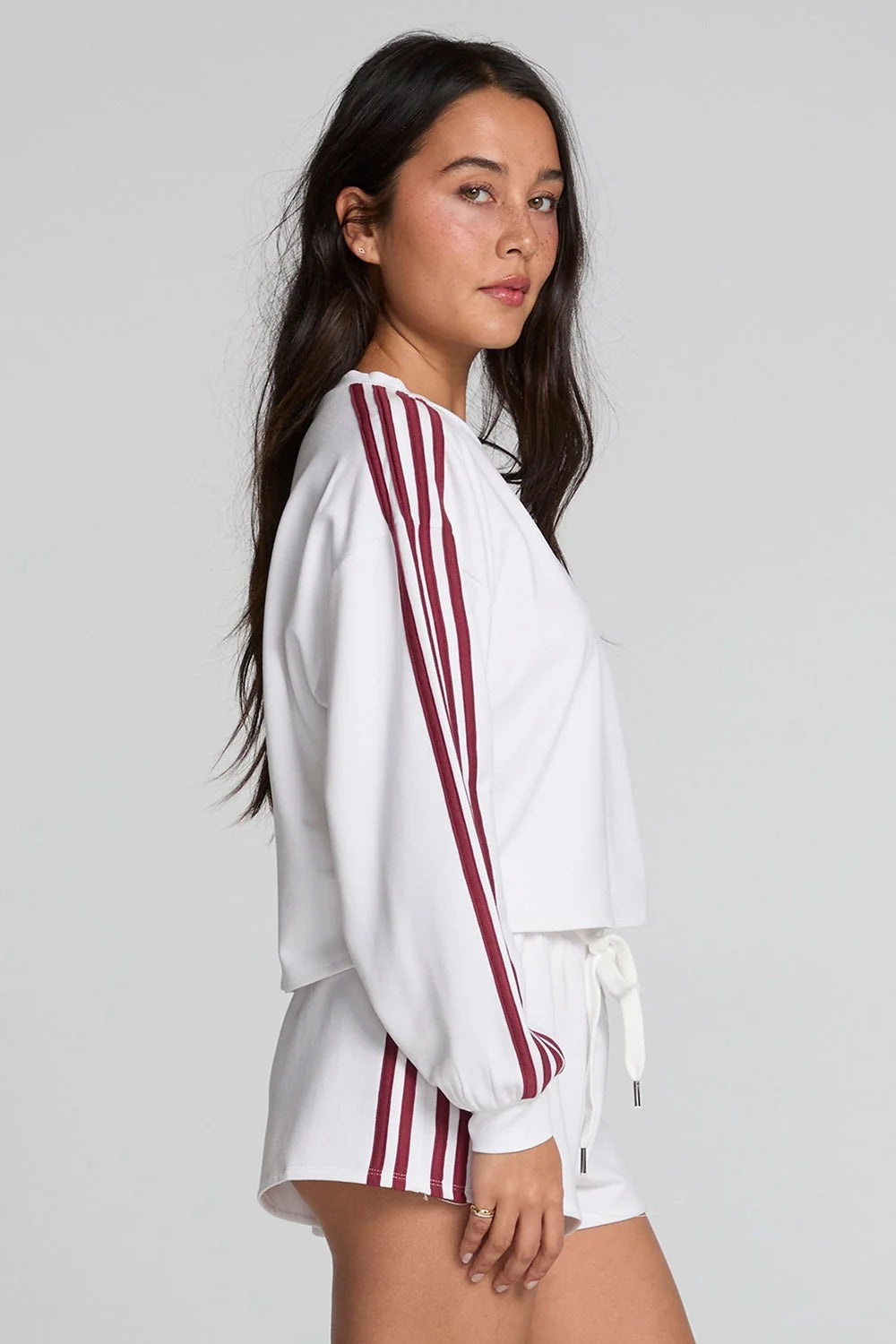 Woman wearing a white outfit with red stripes on a plain background