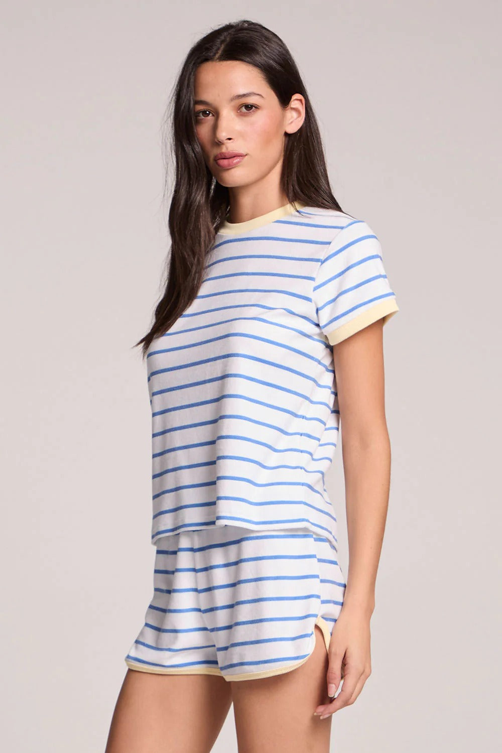 Woman wearing a blue and white striped t-shirt and shorts on a plain background