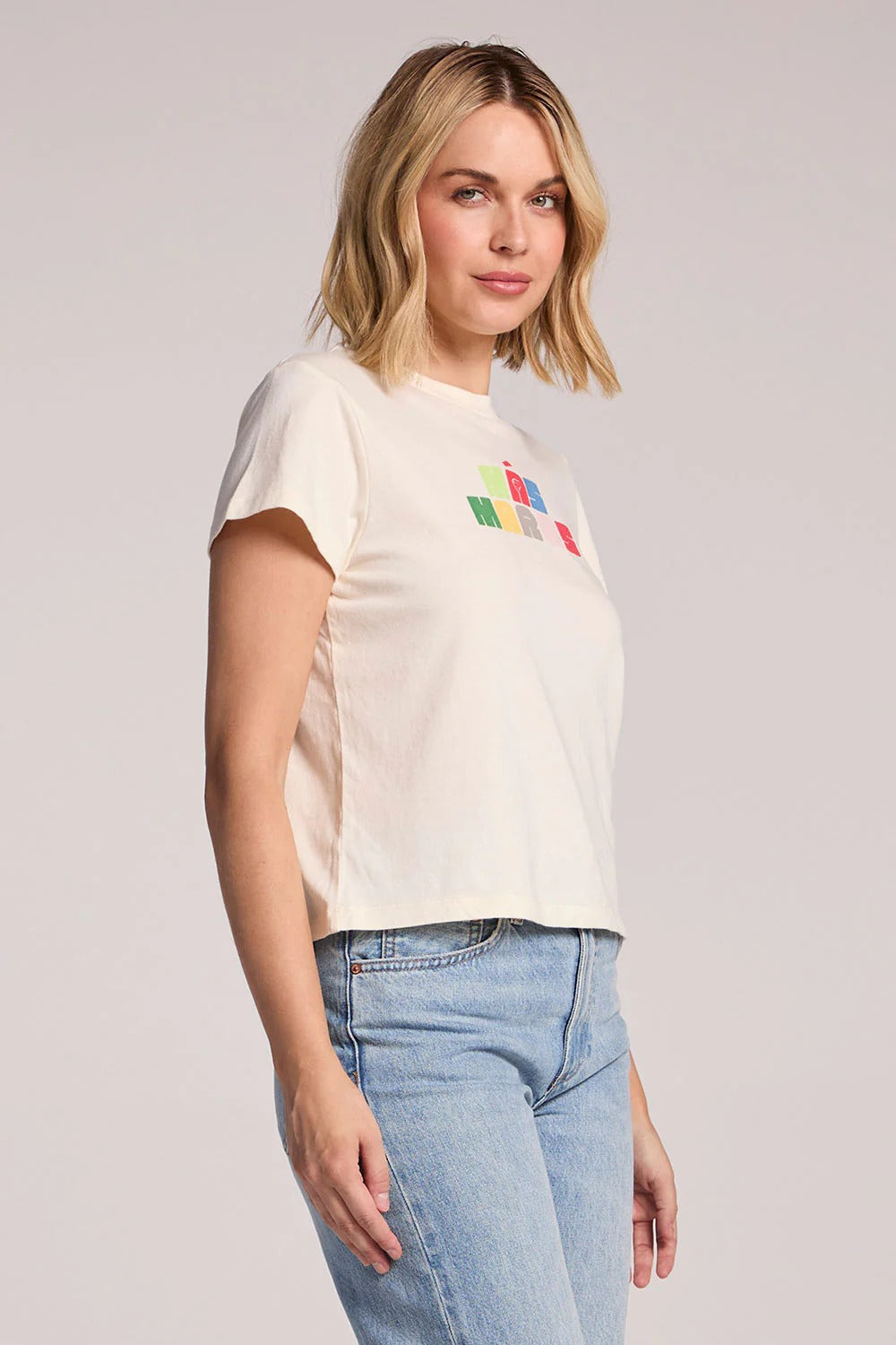 Woman wearing a white t-shirt with colorful graphic design on a plain background