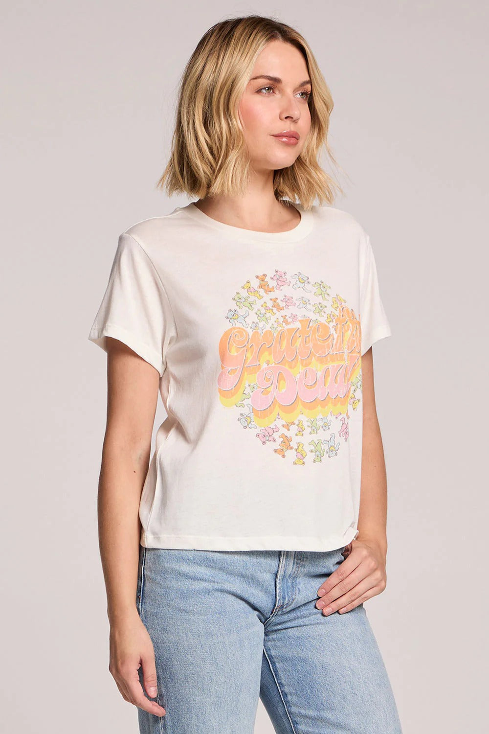 Woman wearing a white t-shirt with colorful text and graphics, standing against a plain background