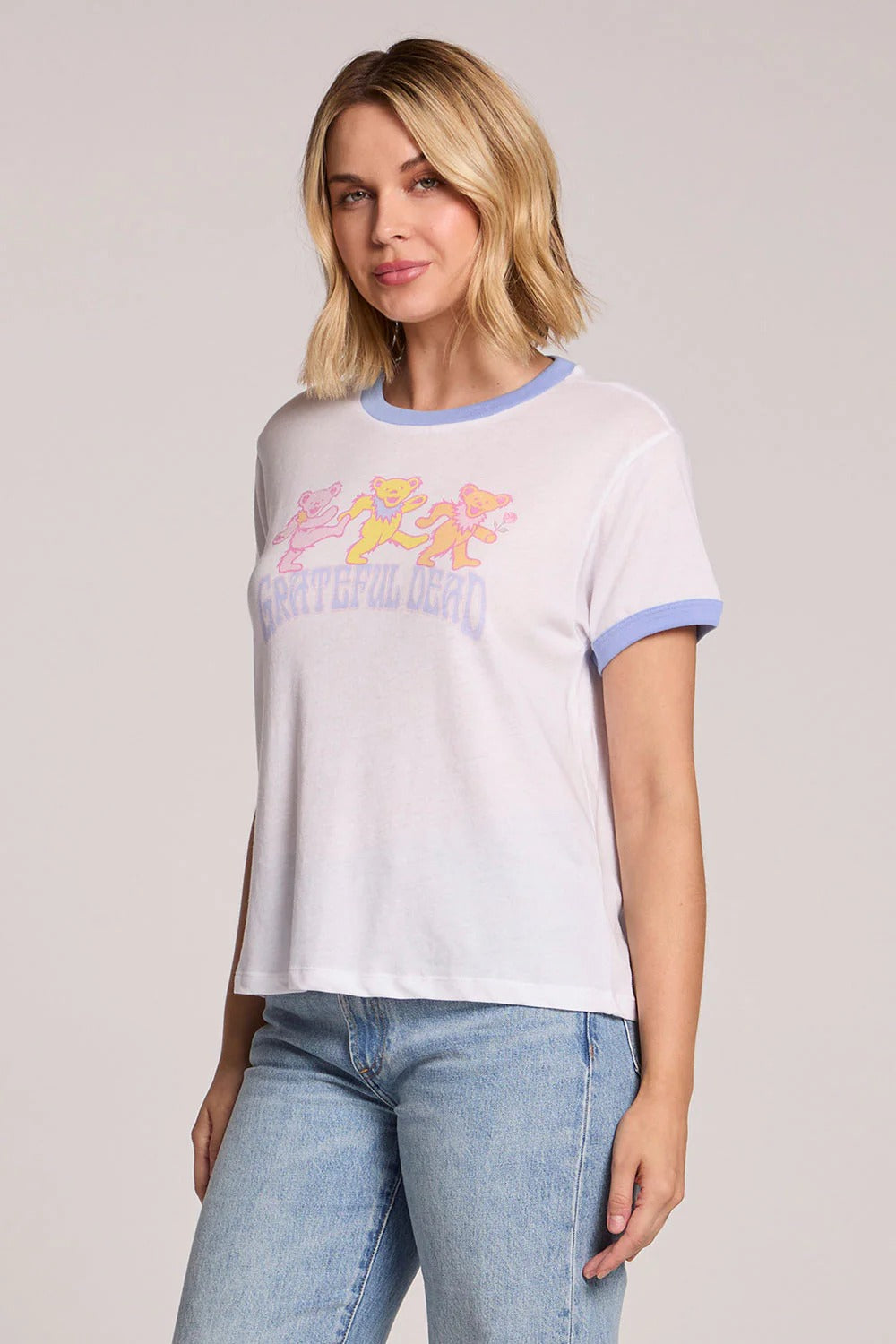 Woman wearing a white t-shirt with colorful graphics and blue jeans on a light gray background