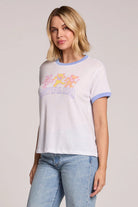 Woman wearing a white t-shirt with colorful graphics and blue jeans on a light gray background