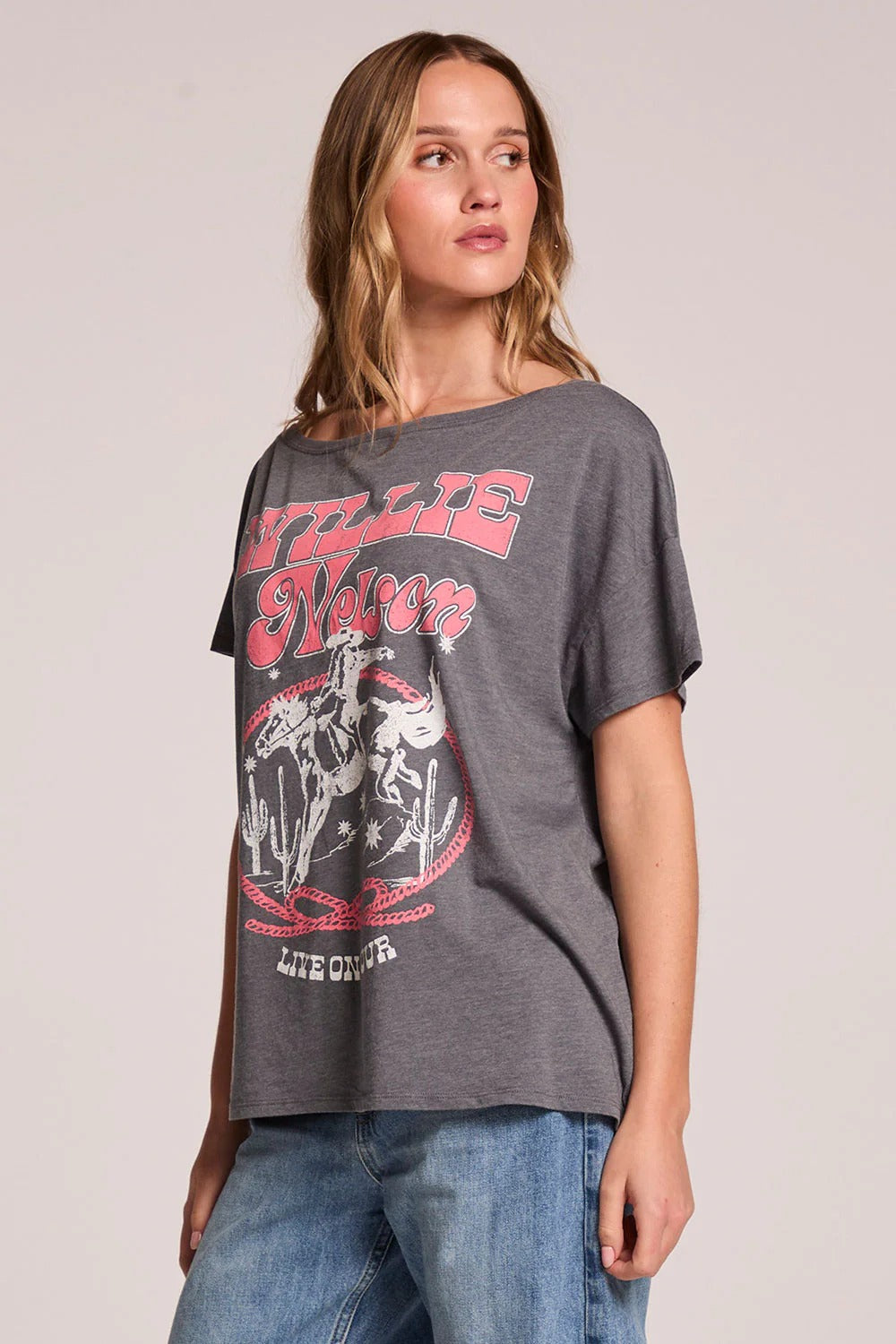 Woman wearing a gray t-shirt with graphic design on a plain background
