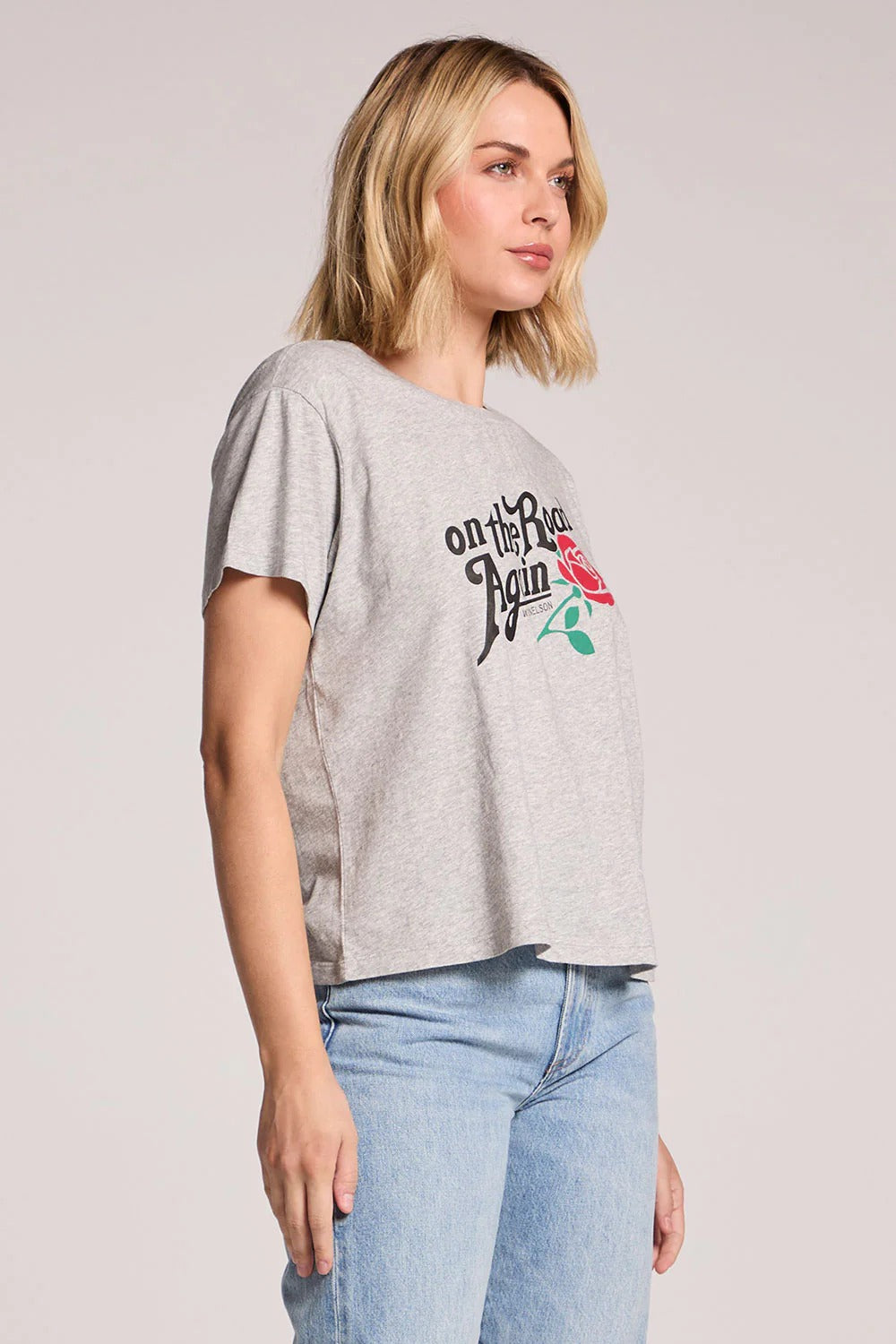 Woman wearing a gray t-shirt with text and graphics on a plain background