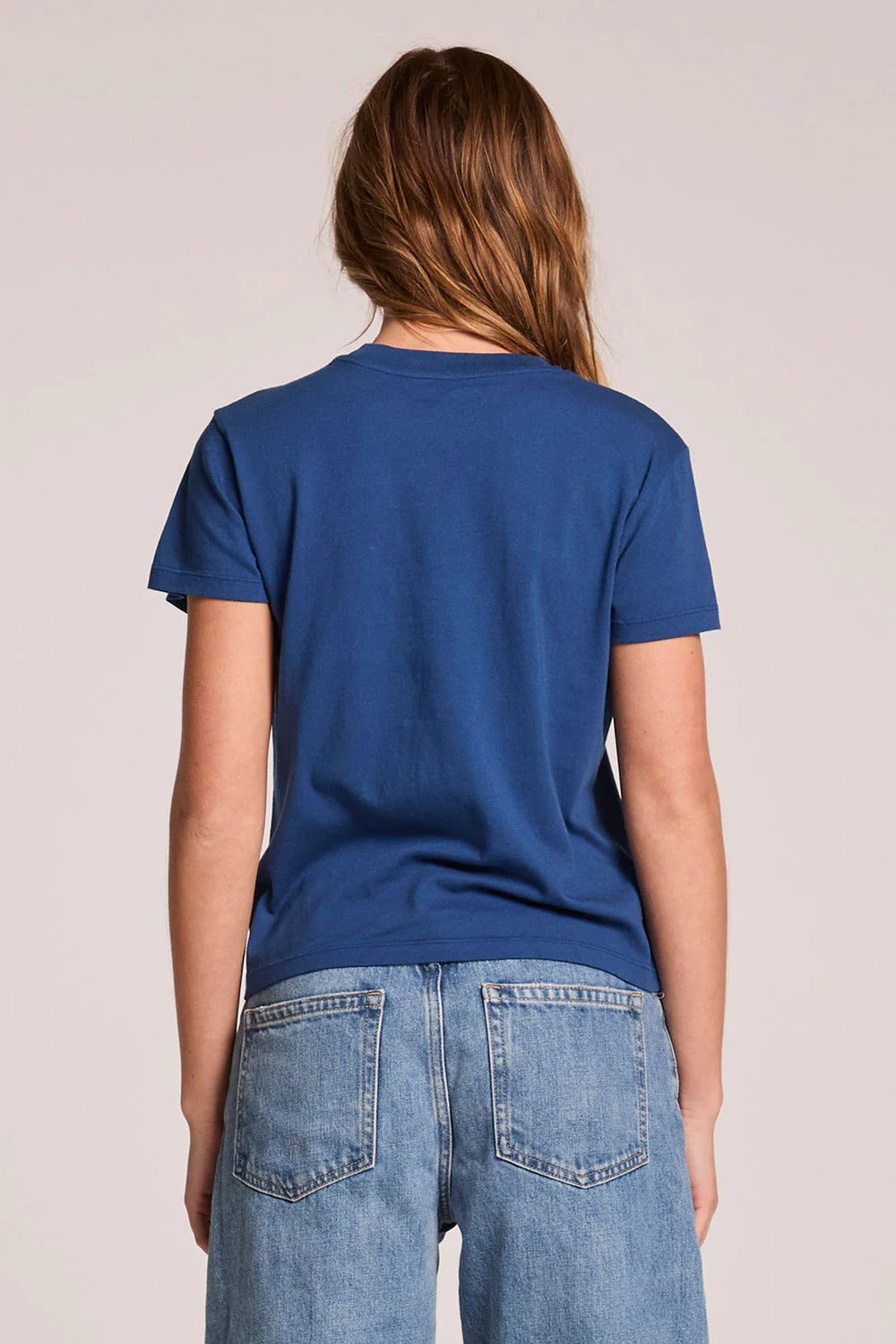 Person wearing a blue t-shirt and jeans on a plain background