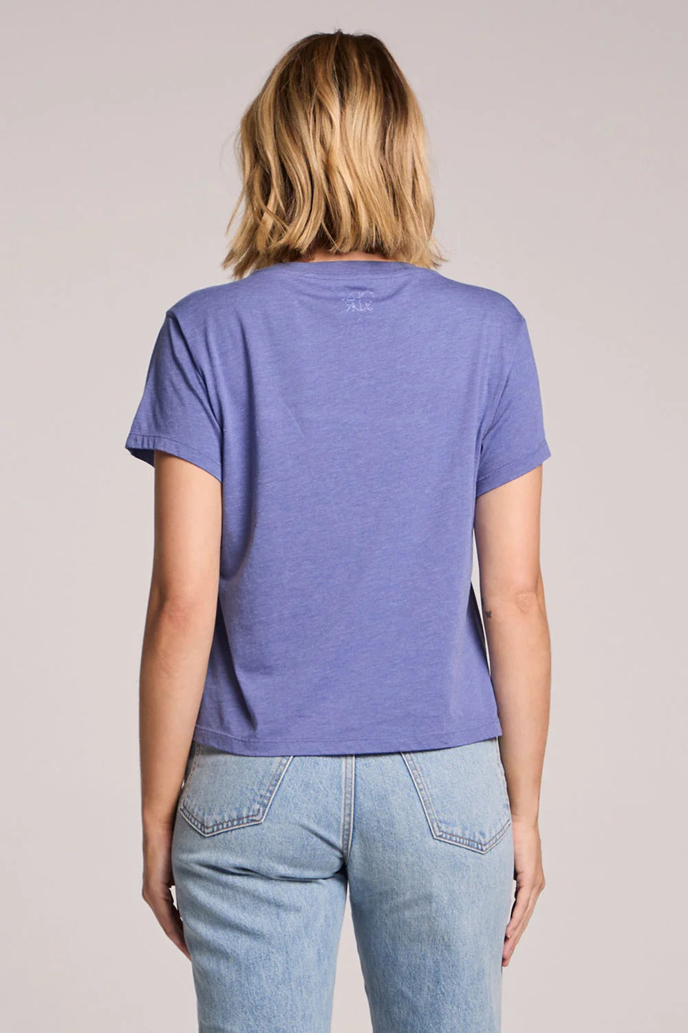 Person wearing a purple t-shirt and blue jeans on a plain background
