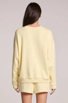 Person wearing a light yellow sweatshirt and shorts set on a plain background