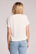 Person wearing a white t-shirt and blue jeans on a plain background