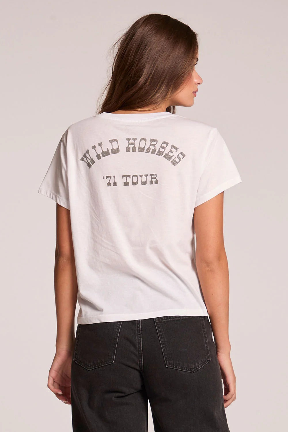 Woman wearing a white t-shirt with 'Wild Horses '71 Tour' text on the back against a plain background