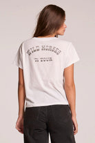 Woman wearing a white t-shirt with 'Wild Horses '71 Tour' text on the back against a plain background