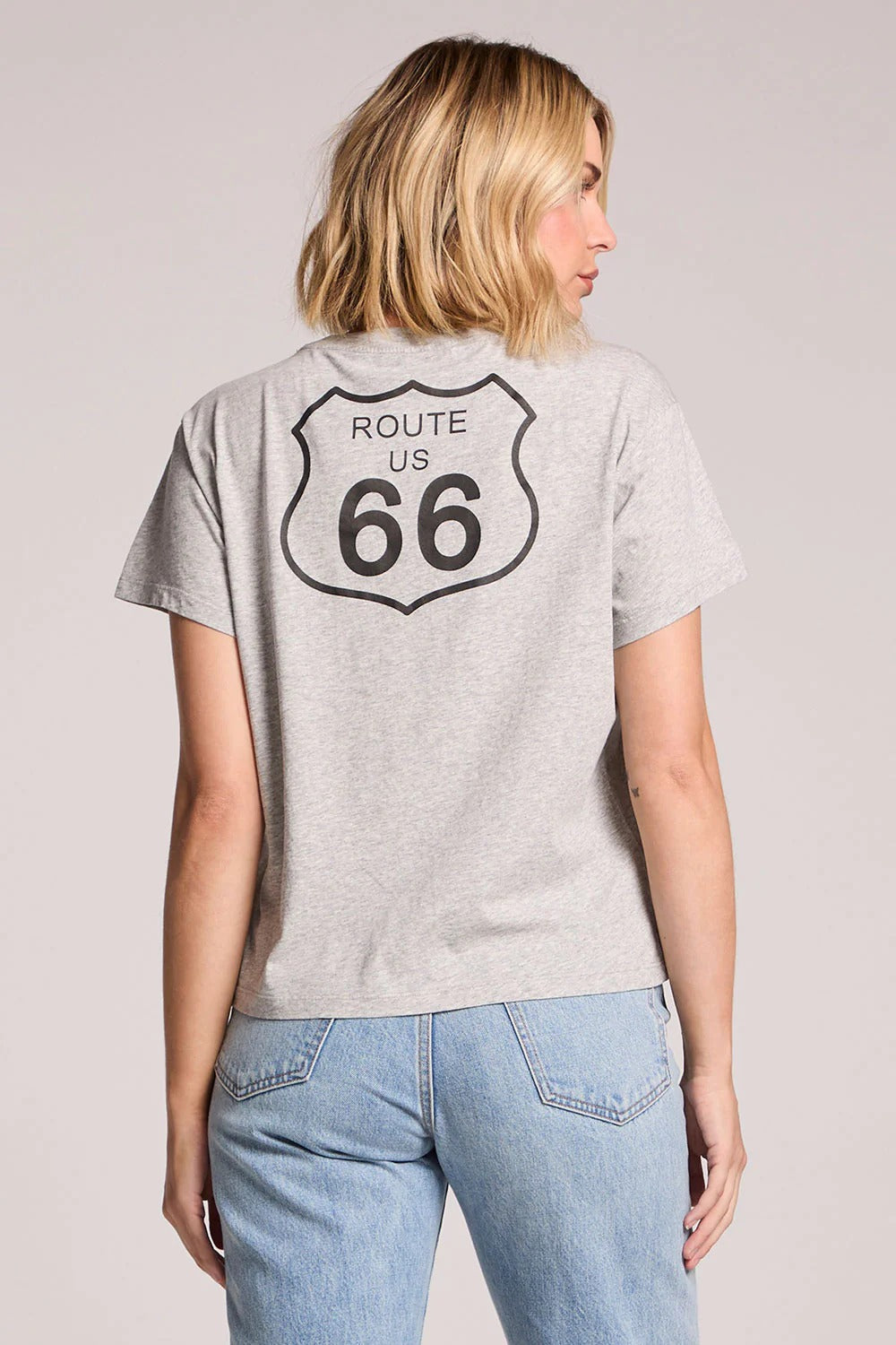 Person wearing a gray t-shirt with Route 66 design on the back, standing against a plain background.