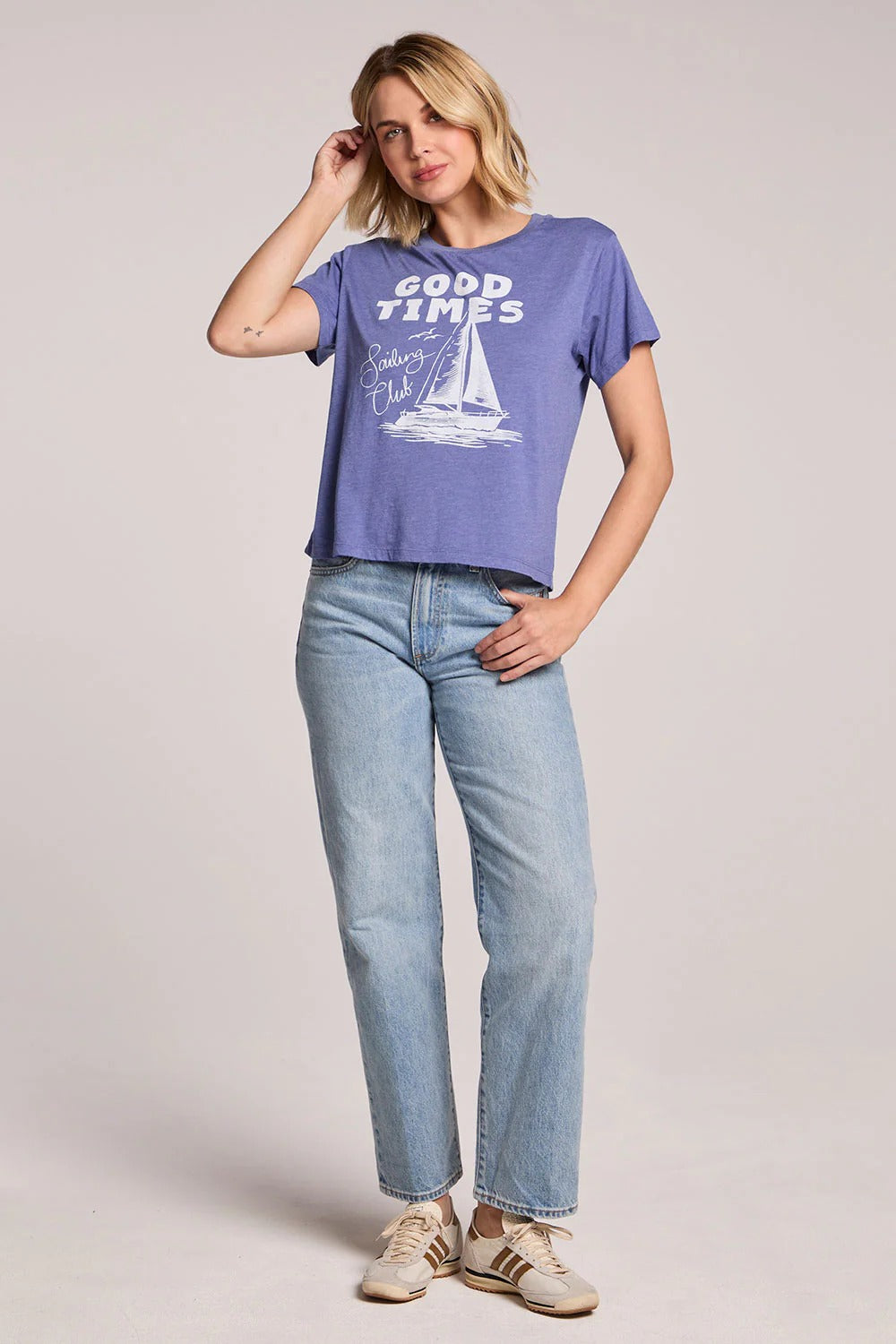 Woman wearing a blue 'Good Times' t-shirt and jeans on a plain background