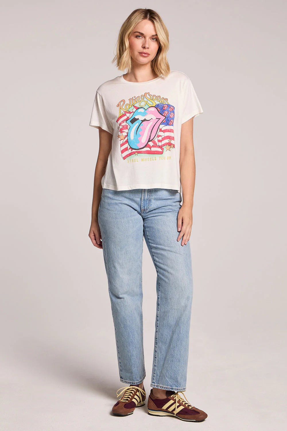 Person wearing a Rolling Stones t-shirt and jeans on a plain background