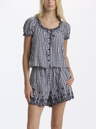 Woman wearing a black and white checkered romper on a white background