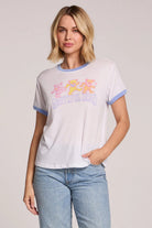 Woman wearing a white t-shirt with colorful graphics and text, standing against a plain background.