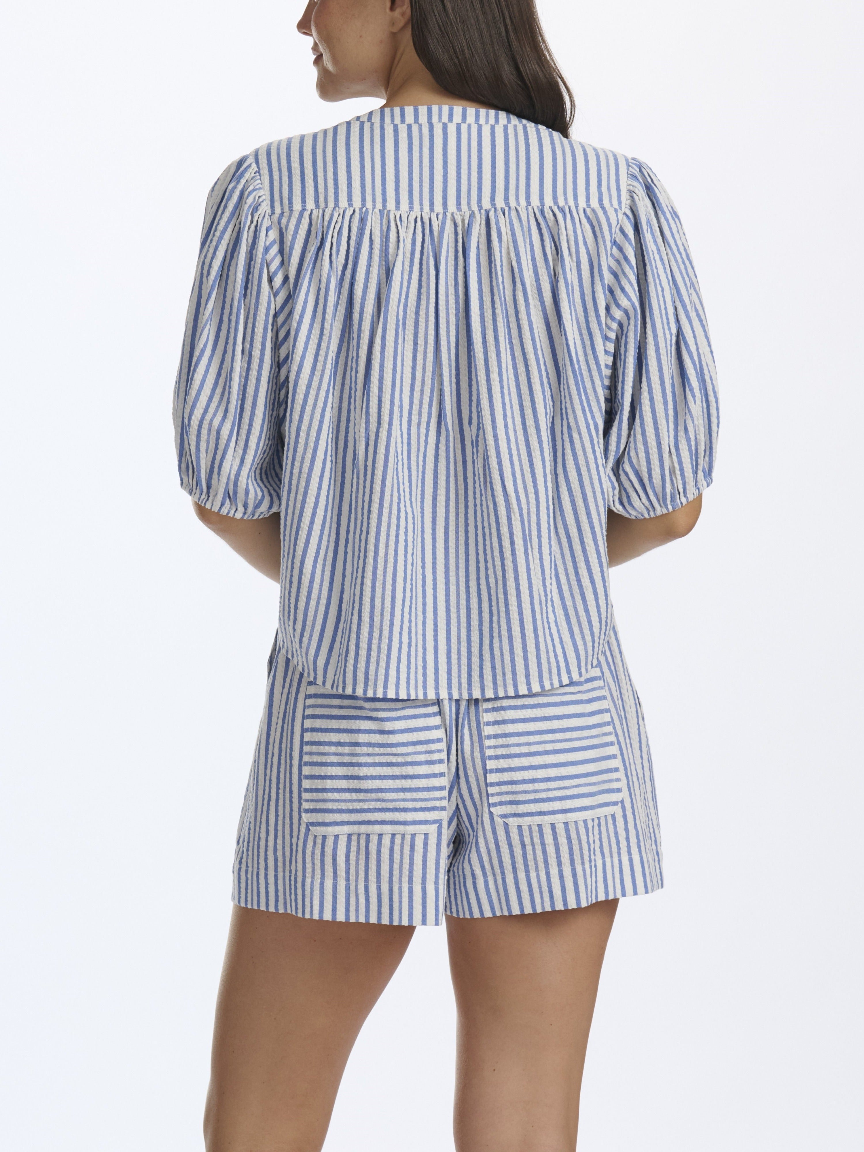 Woman wearing a blue and white striped pajama set on a white background