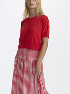 Woman wearing a red top and red checkered skirt on a white background