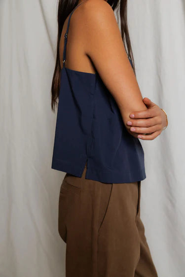 Person wearing a navy blue top and brown pants against a white background